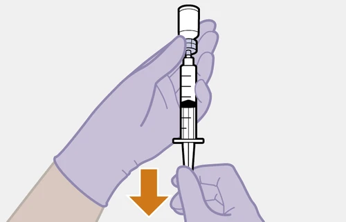 Gloved hands holding a syringe with a vial attached to the top and an orange arrow pointing downward