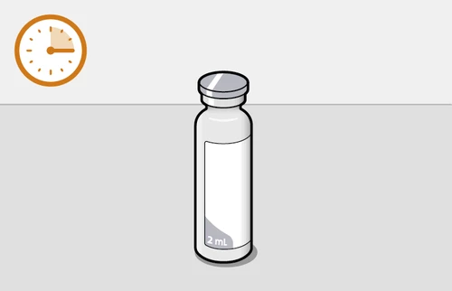 Glass vial with metal cap and white label marked '2 ml' next to an orange analog clock with black hands