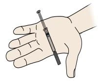 Una mano abierta con los dedos extendidos sostiene una jeringa con aguja y émbolo colocada diagonalmente sobre la palma de la mano