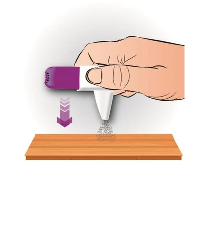 A hand holding a white and purple medical device spraying a mist downward onto a flat wooden surface