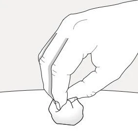 A hand holds a small cotton swab between thumb and index finger above a light-colored flat surface