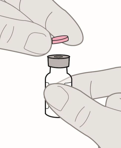 Dos manos sostienen una pequeña pastilla rosa sobre la tapa gris de un frasco de vidrio transparente para la preparación del medicamento