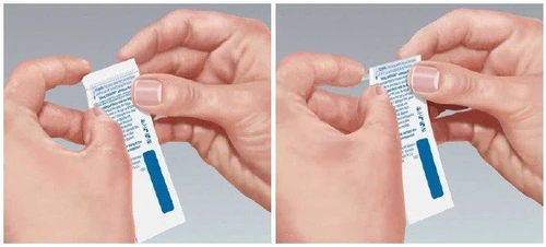 Dos manos sosteniendo y separando un sobre blanco de medicamento con letras azules y una franja vertical azul sobre fondo gris claro