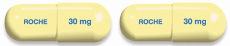 Dos cápsulas amarillas idénticas con la inscripción ROCHE en azul en un lado y la dosis 30 mg en el otro