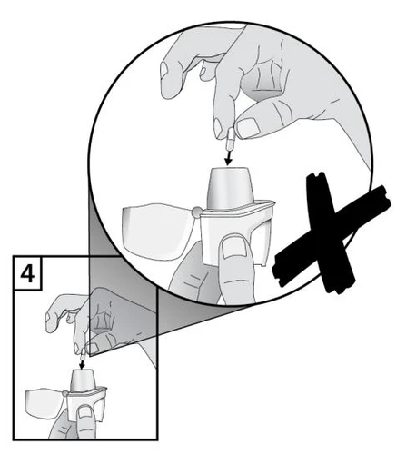 Dibujo en blanco y negro que muestra una mano insertando incorrectamente una cápsula en el dispositivo médico con una gran cruz negra encima