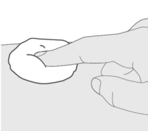 A hand pinches and lifts a skin fold on a flat surface to prepare for injection