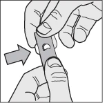 Two hands holding and lifting a thin plastic strip with a central hole indicated by an arrow pointing towards it