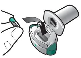 A hand holding a white and green medical device while a protective cap is being removed to expose the top part of the