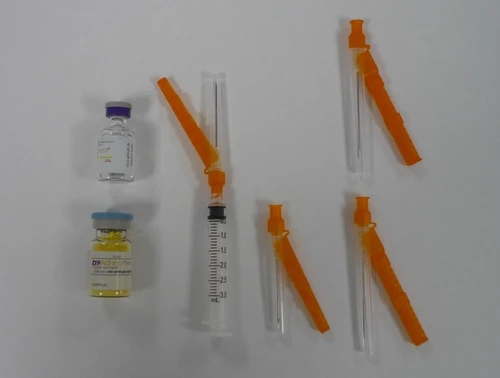 Glass vials with yellow liquid, syringes ready for use