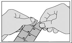 Two hands tearing a paper strip with marked dotted lines to separate individual parts of the medication packaging