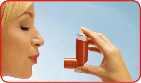 Profilo di una donna con gli occhi chiusi che tiene un inalatore arancione alla bocca per inalare una dose del farmaco su uno sfondo chiaro