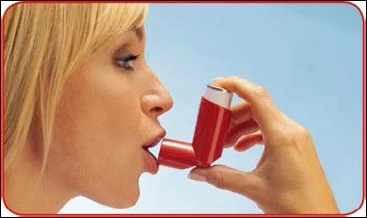 Profilo di una donna bionda che utilizza un inalatore rosso, tenendolo vicino alla bocca per assumere una dose di farmaco su sfondo chiaro
