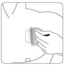 Hand peeling off a patch from a person's abdomen, revealing a medication application site marked with a dashed line