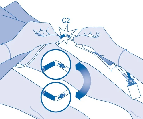 Esquema que muestra dos manos con guantes doblando un tubo C2, con un aumento que ilustra el proceso de doblar en ángulo recto