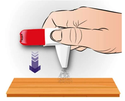 Mano sosteniendo un inhalador blanco y rojo orientado hacia abajo sobre una superficie de madera, de la cual se desprende una fina nube de medicamento bajo una flecha violeta