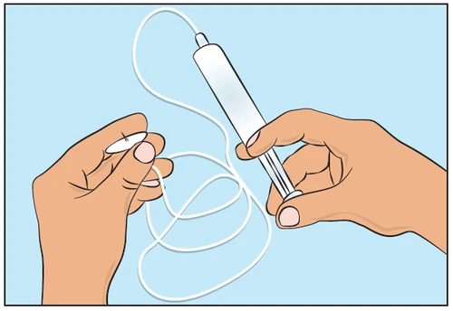 Two hands holding a white cylindrical injector and a long, thin white thread tangled in loops on a light blue background