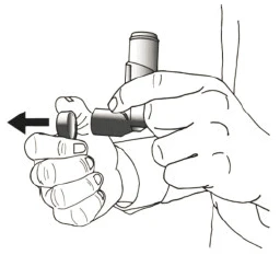 Hands holding a DPI-type inhaler, one hand stabilizing the device while the other slides the cover to the left, indicated by a black arrow