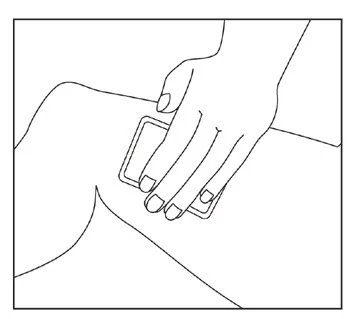 Mano sosteniendo una tirita o vendaje rectangular que se aplica directamente sobre la piel del muslo o cadera de una persona sentada