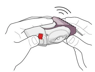 Dos manos sostienen un dispositivo médico blanco y morado, presionando un botón rojo para activar el mecanismo
