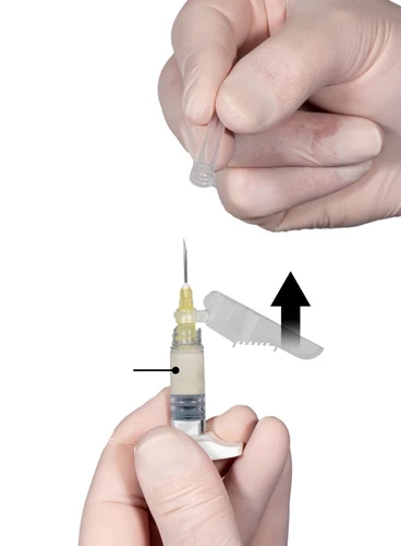 Hands wearing white gloves holding a syringe with a needle, with a black arrow showing the motion of removing the plastic needle shield from the needle tip