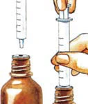 Hands holding a syringe with a needle positioned vertically above an open brown glass medicine vial to draw up the medication