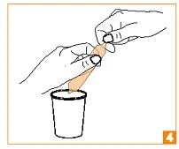 Two hands opening a small package to pour its contents into a white cup placed below on a light background