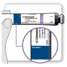 Mano che tiene una fiala del farmaco Genotropin, con ingrandimento circolare dell'etichetta che mostra '12 mg' e spazi per la data di scadenza e il numero di lotto