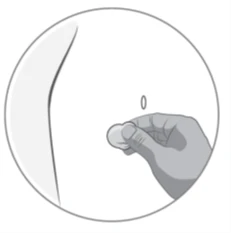 Mano che tiene un cerotto bianco e rotondo e lo applica sulla pelle chiara dell'addome per coprire una piccola ferita o il sito di iniezione