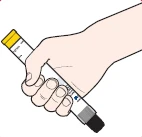 Светлая рука держит белый лечебный ручной шприц с желтым наконечником и черным основанием, установленный под углом на белом фоне