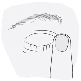 Close-up of a human eye with closed eyelids and eyelashes, with an index finger next to it, ready to apply medication