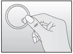 La mano destra tiene tra le dita un anello rotondo e sottile o un elemento medico su sfondo chiaro uniforme