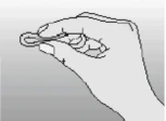 La mano derecha sostiene con los dedos un pequeño objeto redondo que parece una pastilla o cápsula sobre un fondo claro y uniforme