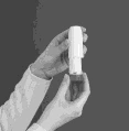 Dos manos sostienen verticalmente un inhalador médico blanco y cilíndrico sobre un fondo oscuro uniforme