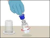 Hand in blue glove opening a medication vial by unscrewing the blue cap, with a transparent cup on a white surface nearby