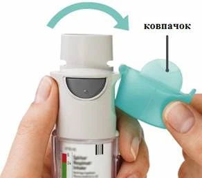 Mano sosteniendo el inhalador, otra mano abre la tapa que protege la boquilla, una flecha verde indica la dirección de apertura