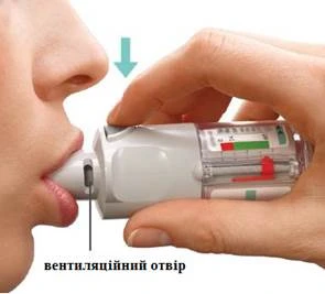 Mano sosteniendo el inhalador introducido en la boca, con la marca del orificio de ventilación y una flecha que indica la dirección de la inhalación