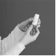 Una mano tiene un flacone bianco con erogatore, pronto all'uso per applicare il farmaco sulla pelle